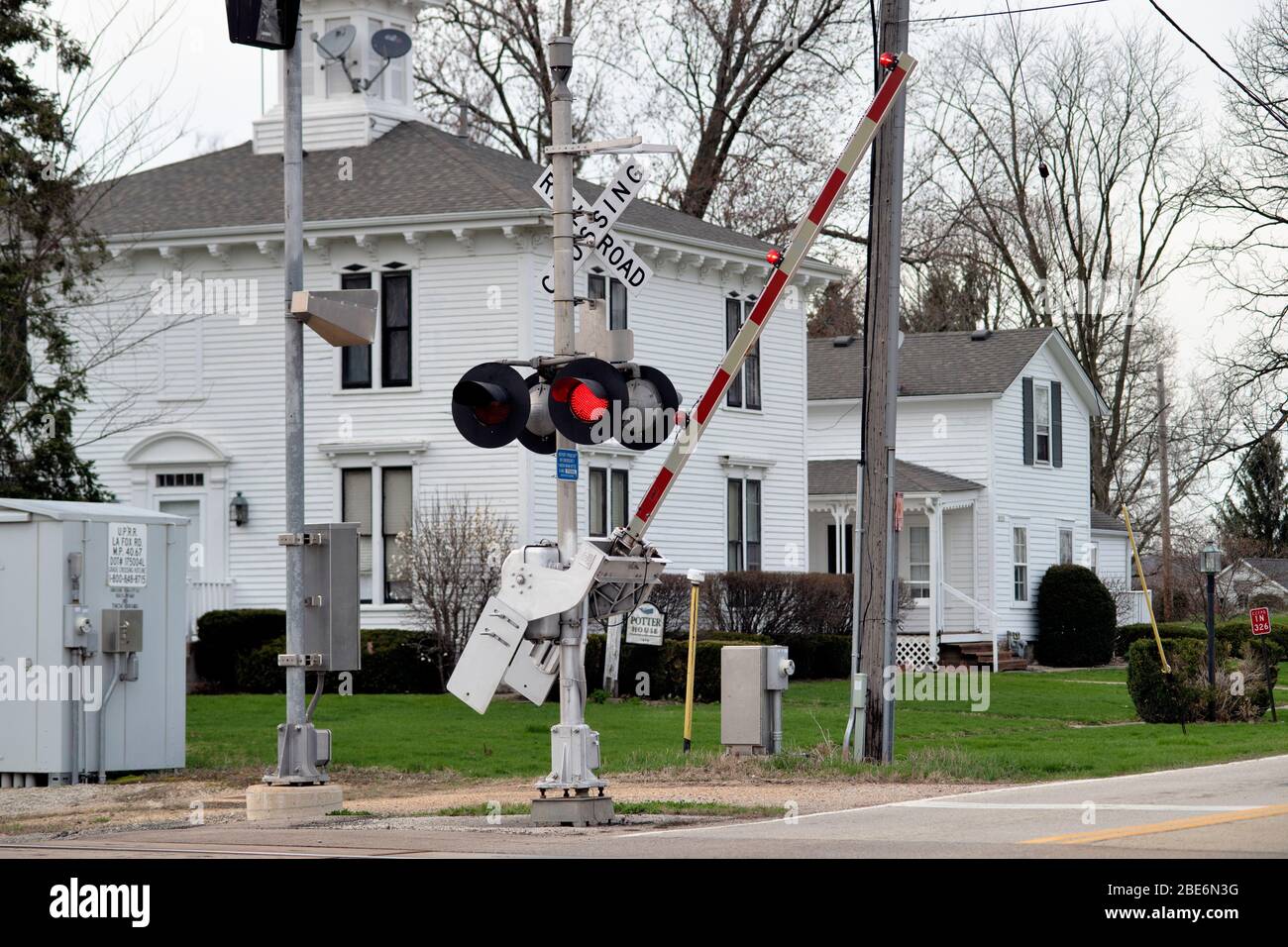 Lafox, Illinois, Stati Uniti. Un cancello di attraversamento stradale scende con luci rosse lampeggianti per avvisare gli automobilisti di un treno di trasporto imminente. Foto Stock