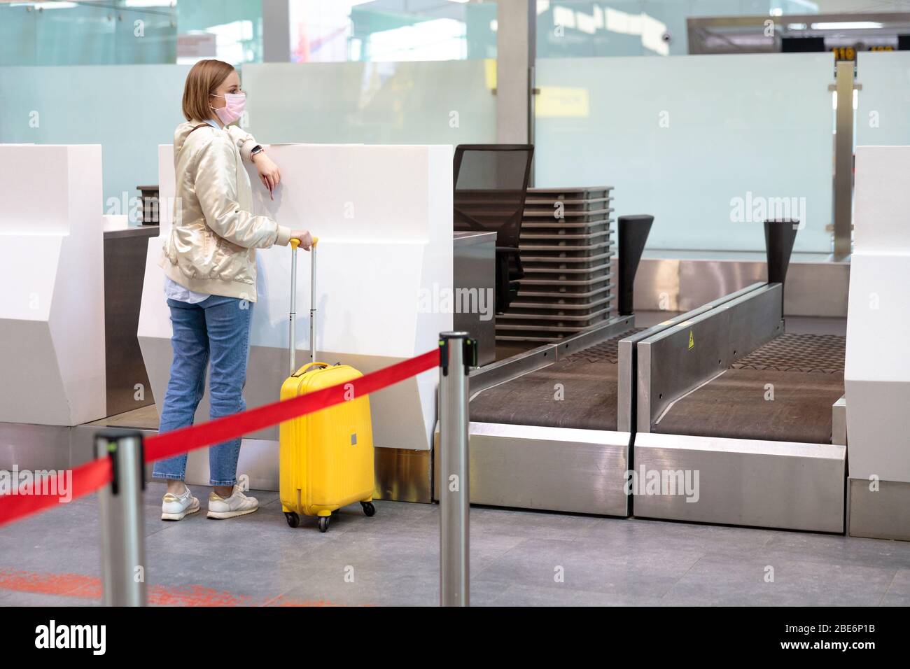 Donna con bagagli in caso di cancellazione del volo, si trova in banchi di check-in vuoti presso il terminal dell'aeroporto a causa di coronavirus pandemia/Covid-19 scoppio di traverve Foto Stock
