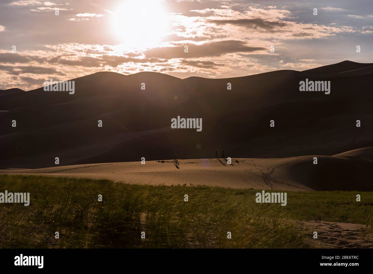 Tramonto al Great Sand Dunes National Park, Colorado, USA, che si staglia sulle dune di sabbia con alcune persone inidentificabili in lontananza. Foto Stock