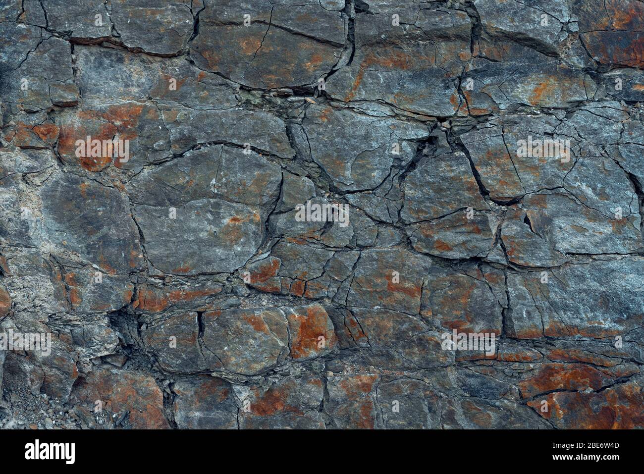 Parete naturale di roccia basaltica con crepe e fessure. Struttura rocciosa. Pietra grafite wall.Stone sfondo. Fotografia fatta con luce naturale. Texture Foto Stock