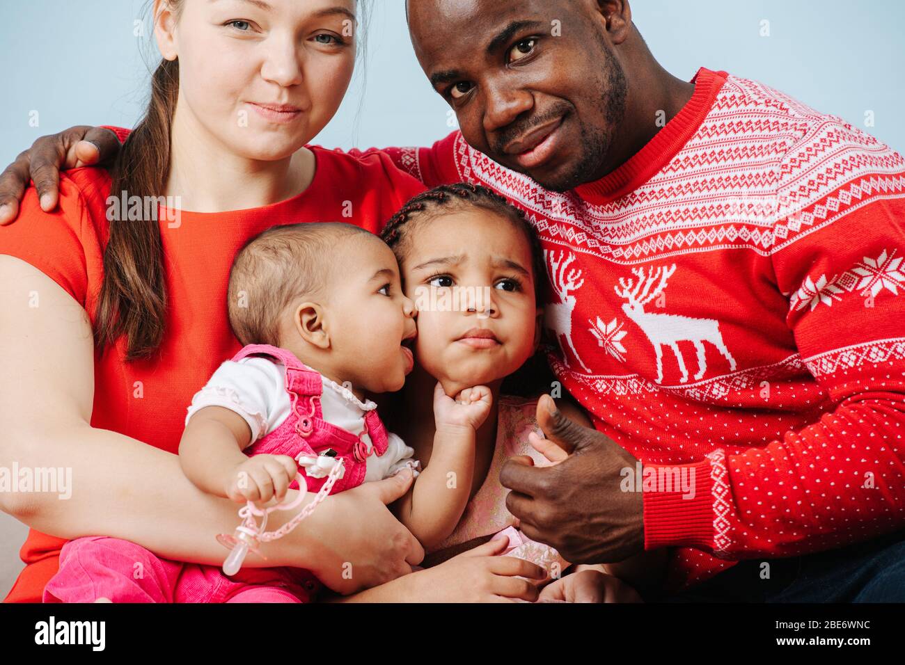 Genitori felici in abiti rossi luminosi che posano con i bambini per una foto di famiglia Foto Stock