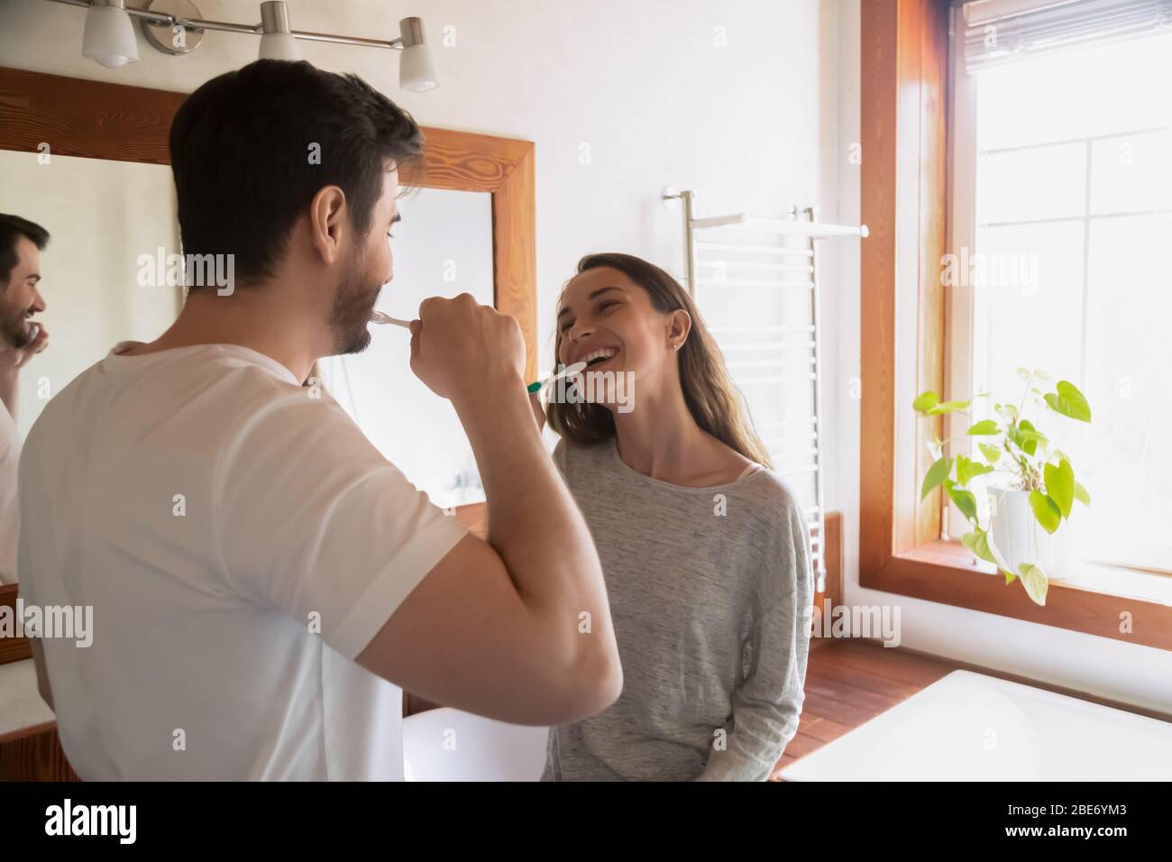 Sposi giovani e gioiosi che si guardano l'un l'altro, pulendo i denti. Foto Stock