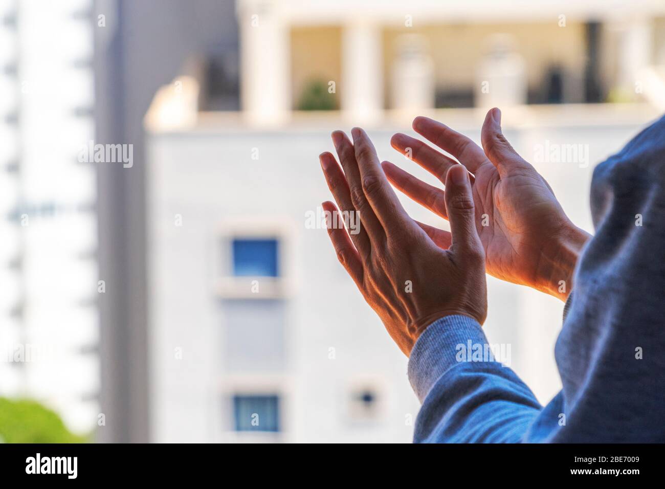 Donna mani applauding dal suo balcone per sostenere il personale medico, gli operatori sanitari, medici, infermieri durante la pandemia di Coronavirus Foto Stock