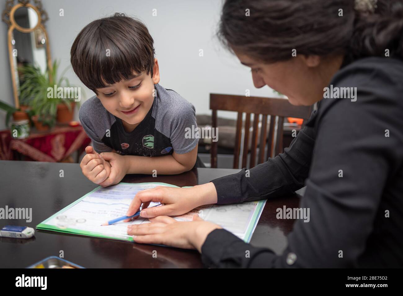 Mamma che insegna e aiuta suo figlio a fare lavoro a casa, scuola a casa in mezzo allo scoppio del covid-19 Foto Stock