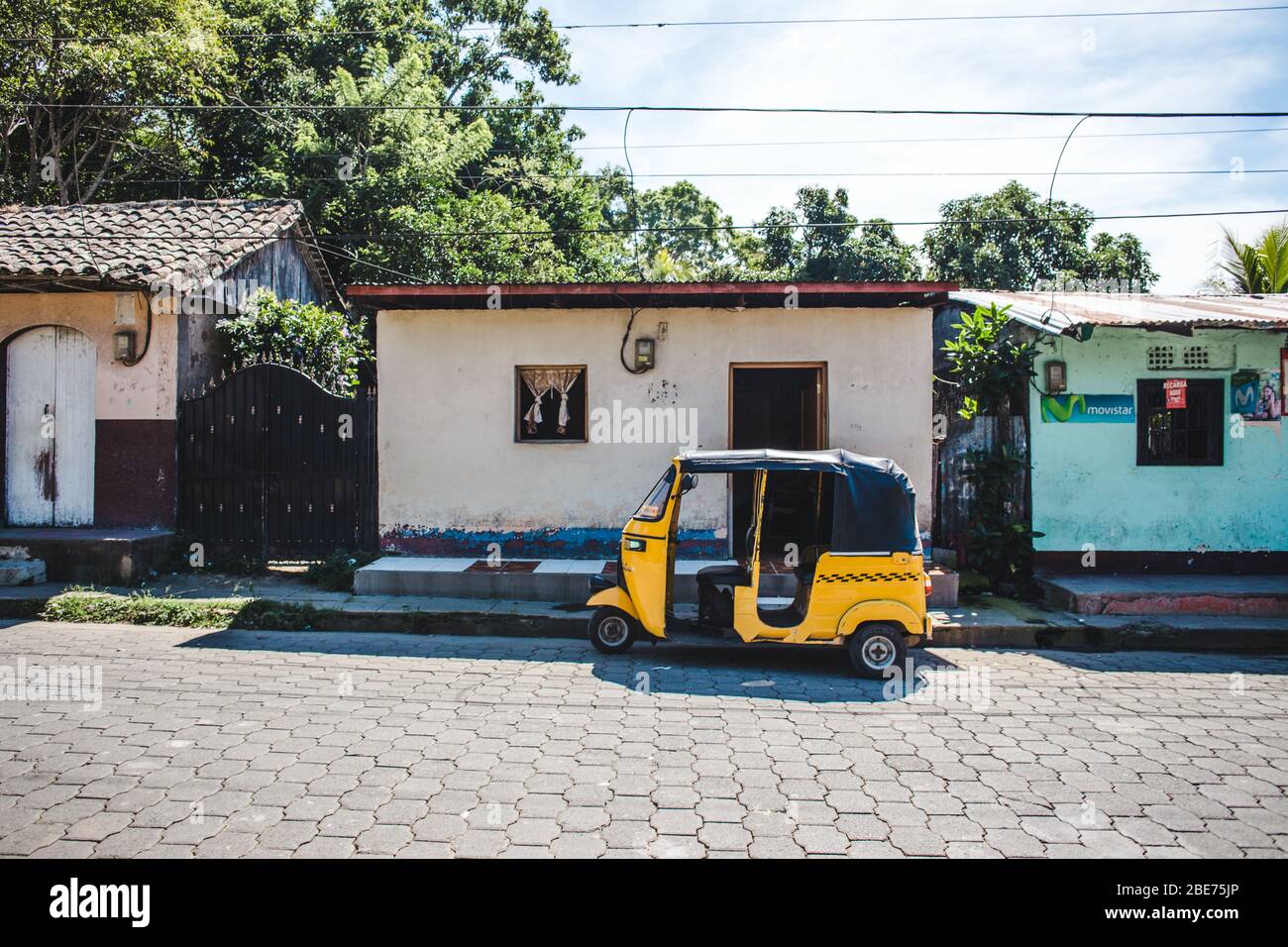 Tuktuk giallo parcheggiato fuori una piccola casa a Pacaya, Nicaragua Foto Stock