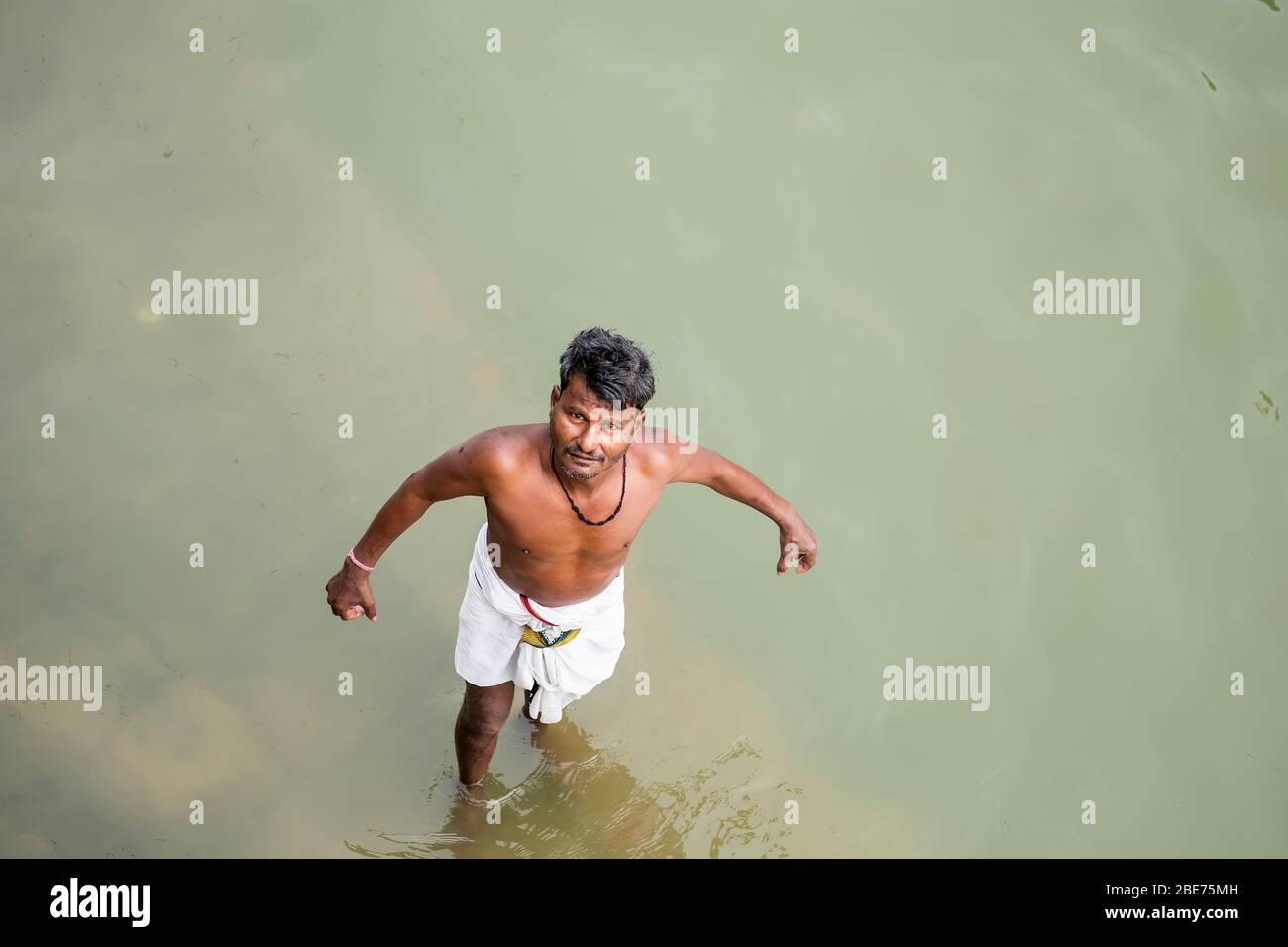 Uomo indiano che fa un tuffo nel fiume di Ganga (Ganges) a Varanasi, India Foto Stock