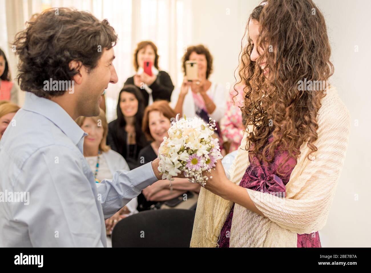 Coppia appena sposata in una cerimonia civile dove si apprezzano espressioni sorridenti e bouquet nuziale. Sullo sfondo si può vedere il felice e SM Foto Stock