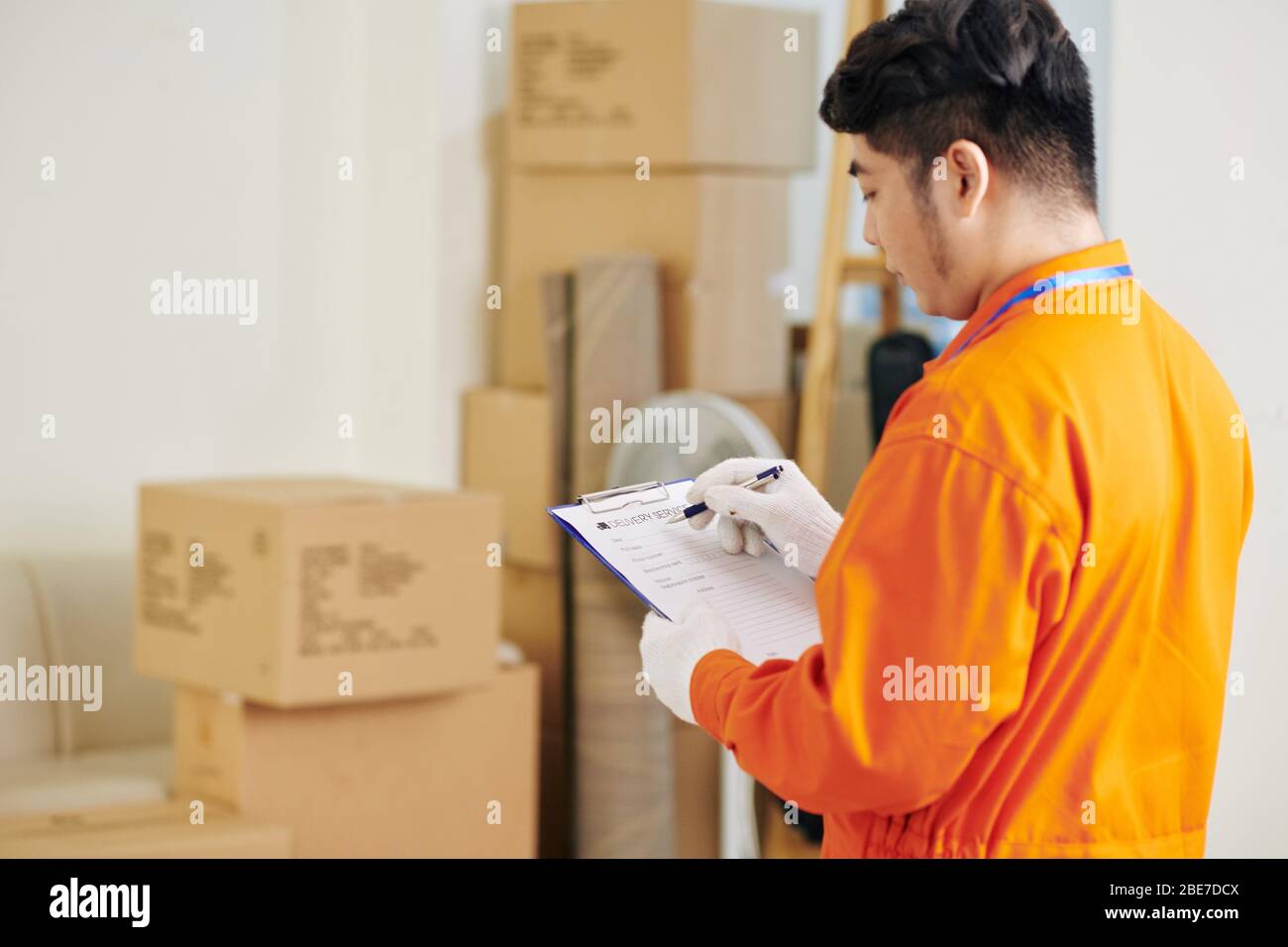 Mover che compila il documento di servizio di consegna con i dettagli prima di iniziare il lavoro Foto Stock