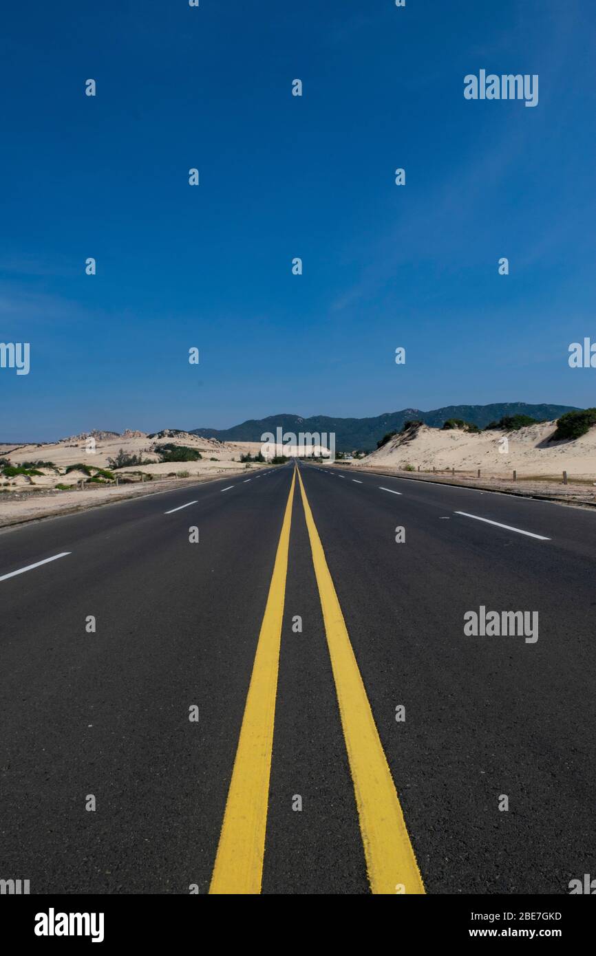 Strada costiera vuota circondata da sabbia Foto Stock