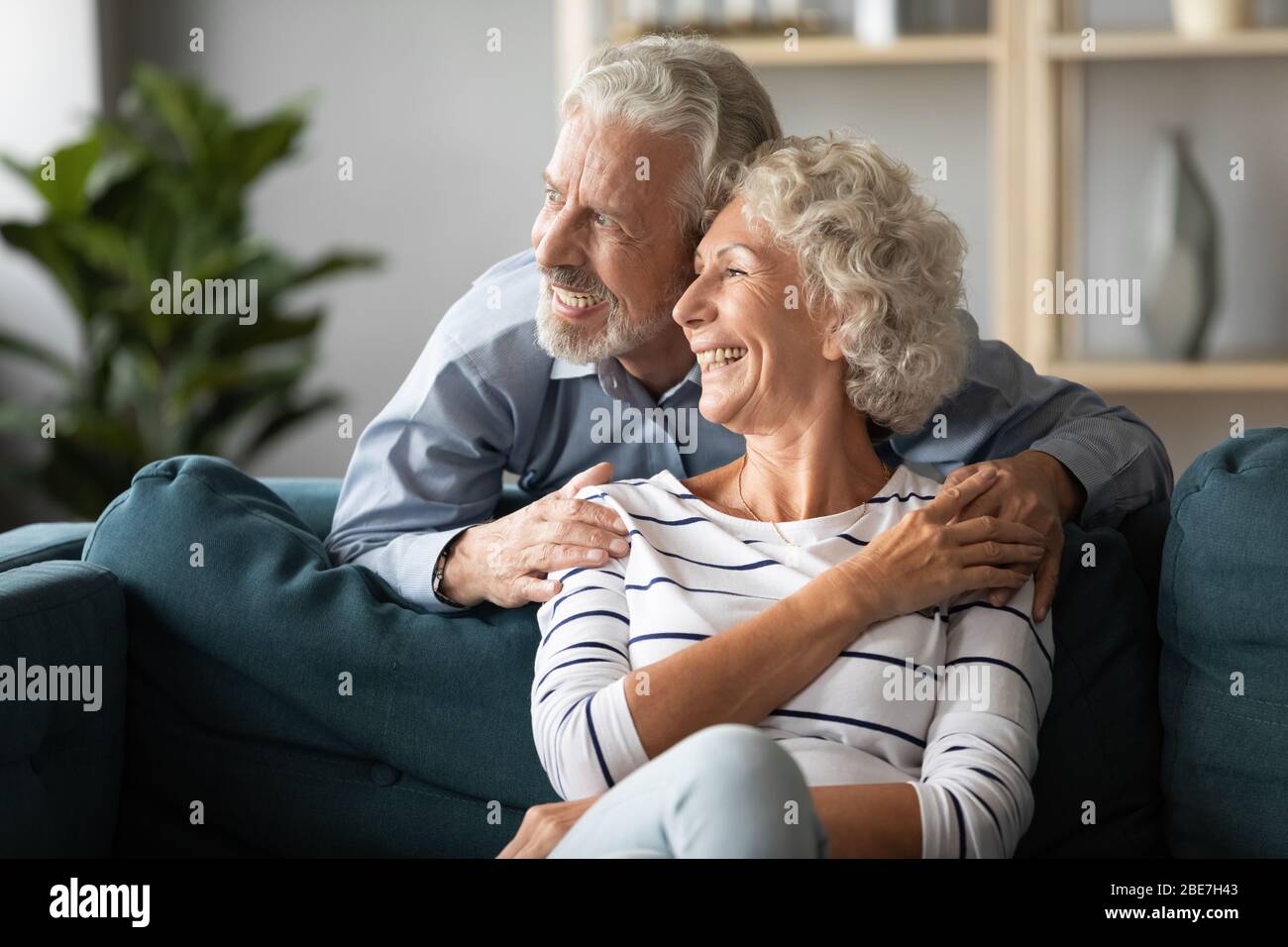 Sorridendo coppia più vecchia sognando insieme, guardando fuori la finestra Foto Stock
