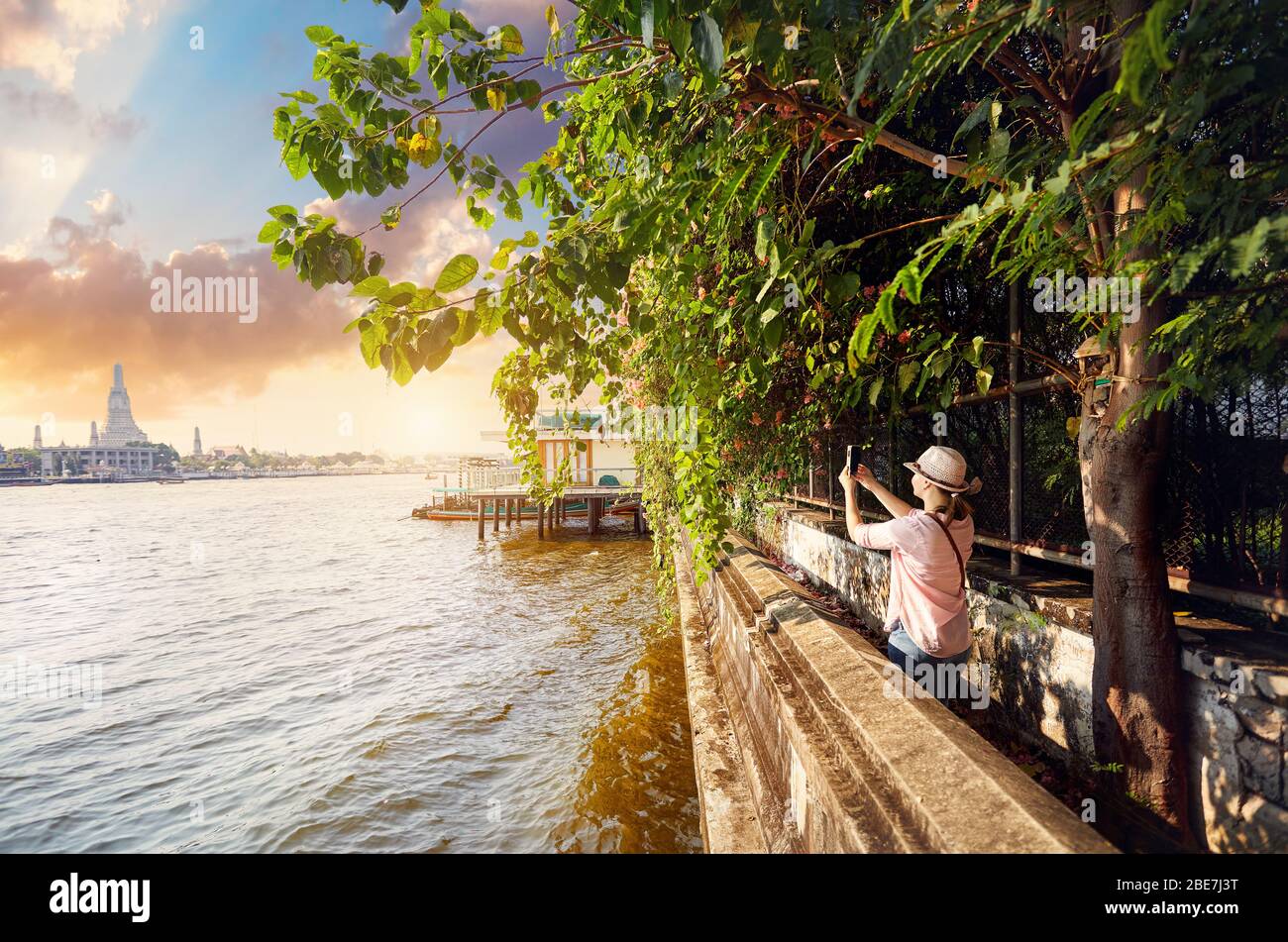 Donna turistica prendendo un'immagine di Wat Arun con il suo telefono al tramonto a Bangkok, in Thailandia Foto Stock