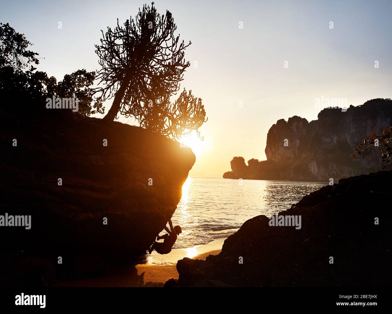 Rocciatore in silhouette a Tonsai spiaggia al tramonto a Krabi, Thailandia Foto Stock