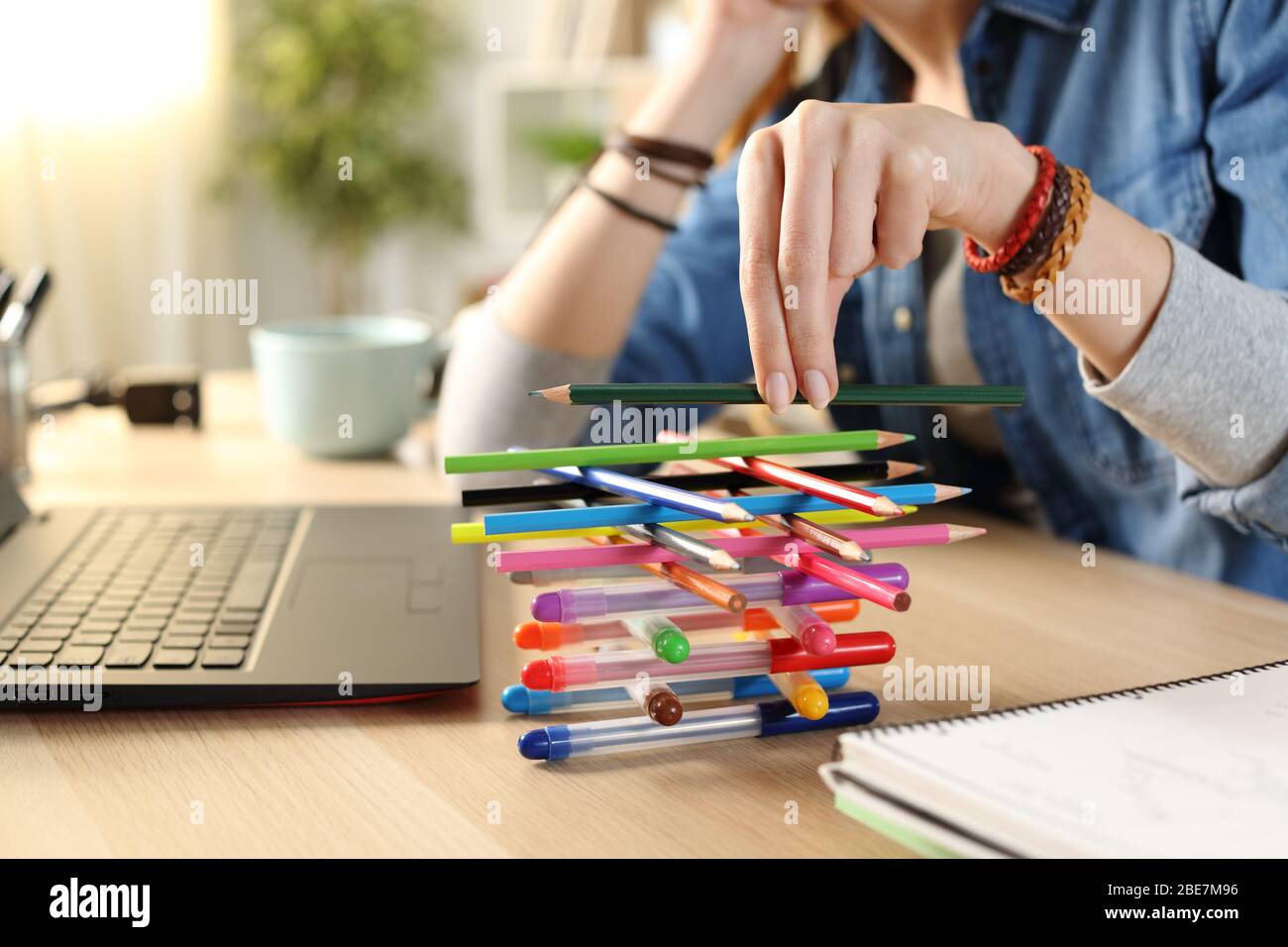 Annoiato lazy studentessa mani perdere tempo giocando con penne seduta su una scrivania a casa Foto Stock