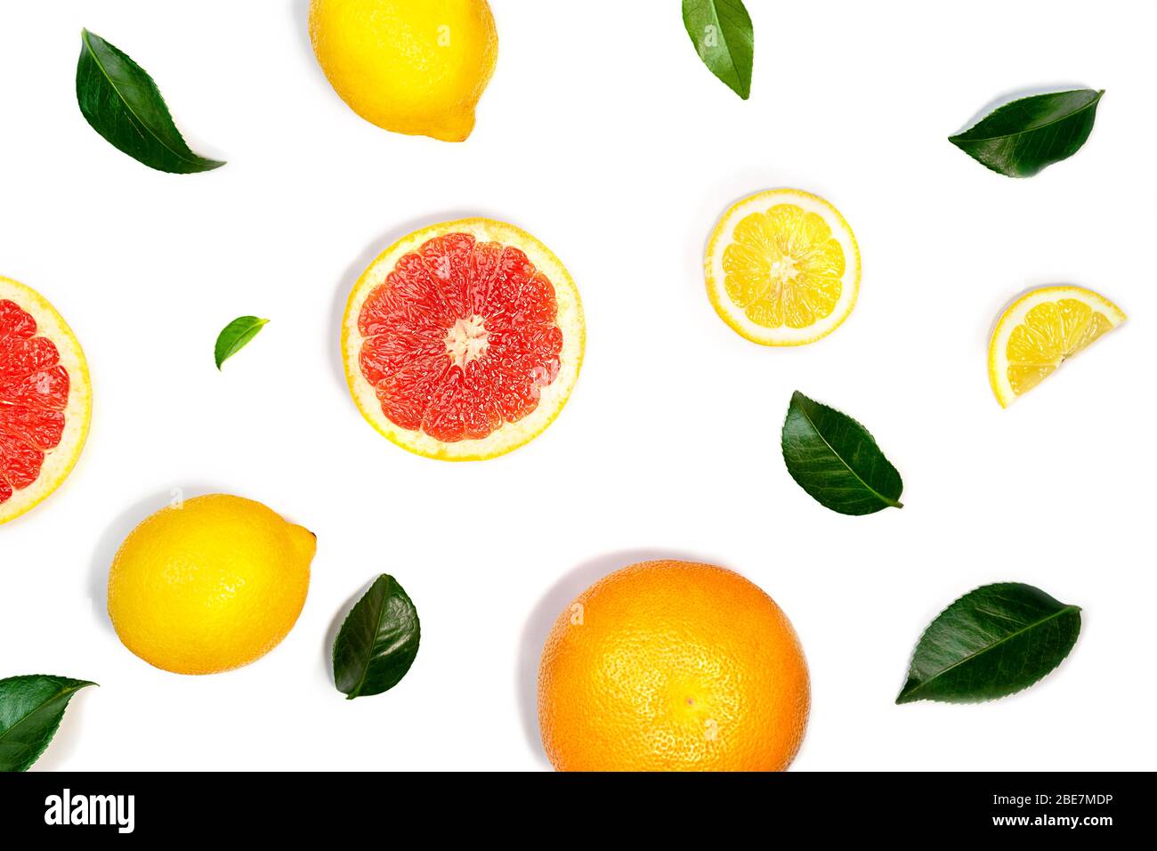 Layout creativo a base di limone, pompelmo e foglie verdi su sfondo bianco. Disposizione piatta, primo piano. Concetto di cibo tropicale. Foto Stock