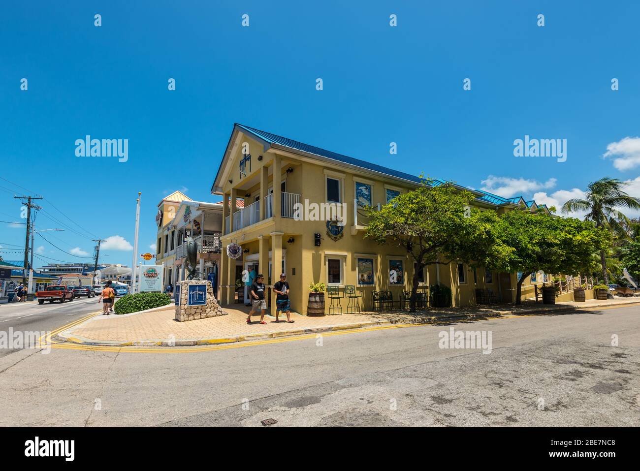 George Town, Grand Cayman Island, Regno Unito - 23 aprile 2019: Vista della strada di George Town di giorno con i pedoni e la scultura di pesce vicino al ristorante in basso Foto Stock