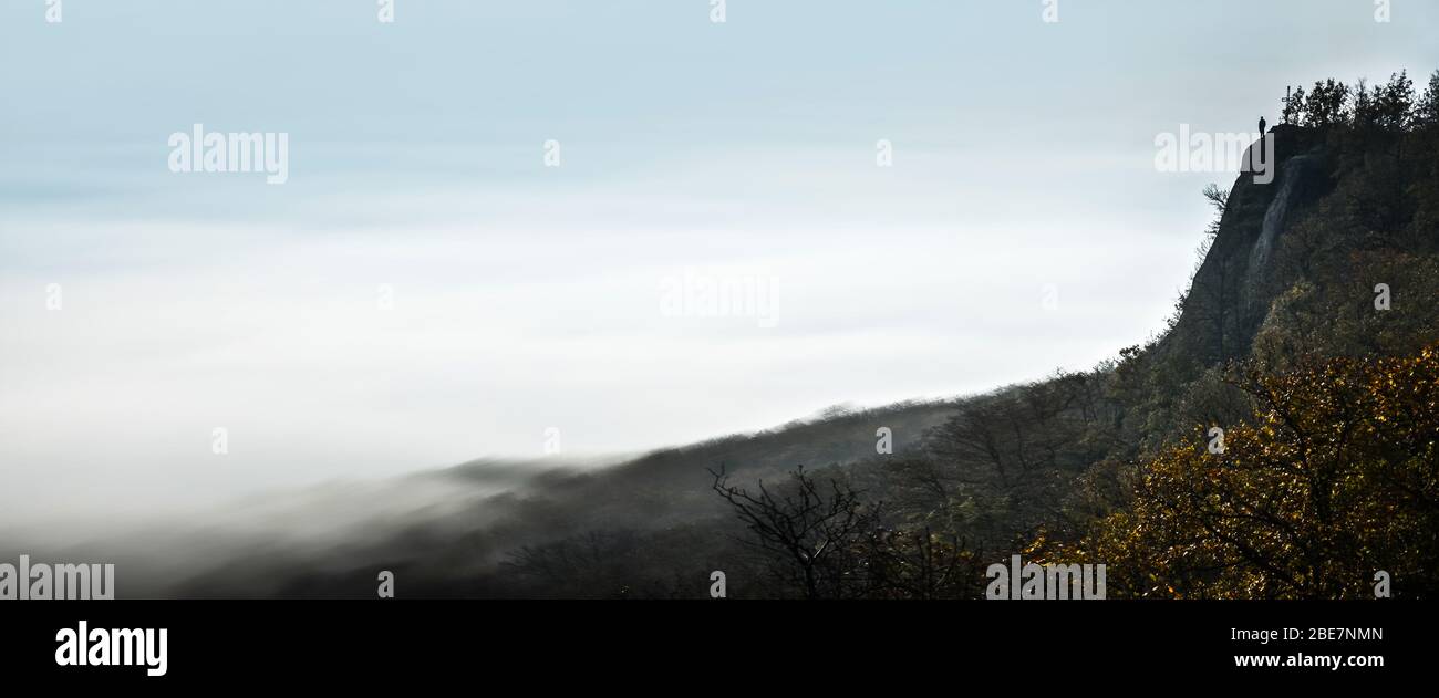 Banner, pagina web o copertina di solo uomo in piedi sulla cima delle rocce sopra la valle piena di nebbia - pensando, triste, solo, depressione conce Foto Stock