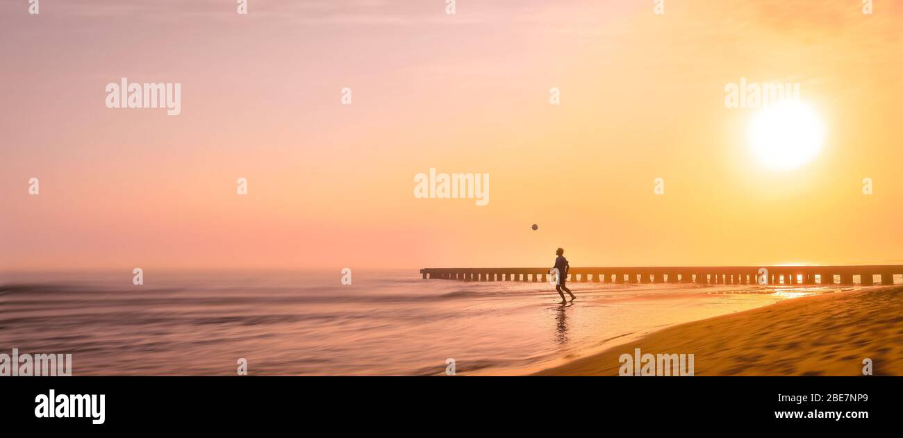 Banner, pagina web o template di copertina del giocatore di calcio giovane sta giocando con il pallone sulla bellissima spiaggia di Misty mattina in Brasile. Spazio di copia e pa Foto Stock