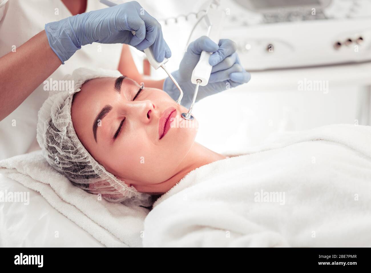 Pulizia profonda dei macchinari. Donna d'affari con occhi scuri che chiude gli occhi avendo macchinari pulizia profonda del viso Foto Stock