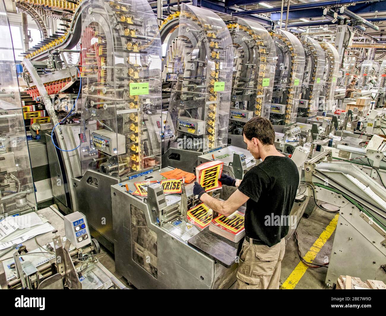 Lavoratore in un negozio di stampa di fronte a grandi presse da stampa,  fogli stampati con crisi di iscrizione, Baden-Wuerttemberg, Germania Foto  stock - Alamy