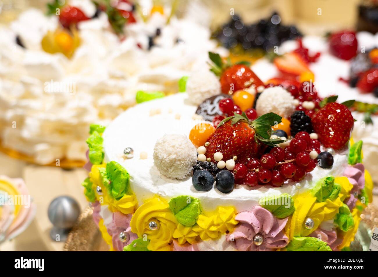 Torte e pasticcini in una vetrina. Pasticceria con varietà di ciambelle, crème brulee, torte con frutta e frutti di bosco Foto Stock