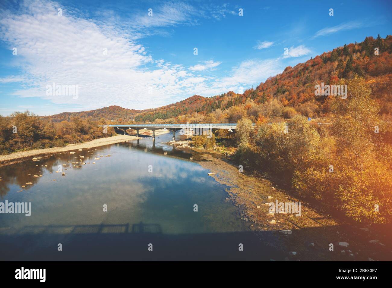 Vista panoramica di una valle di montagna con fiume e ponte in autunno. Foto Stock