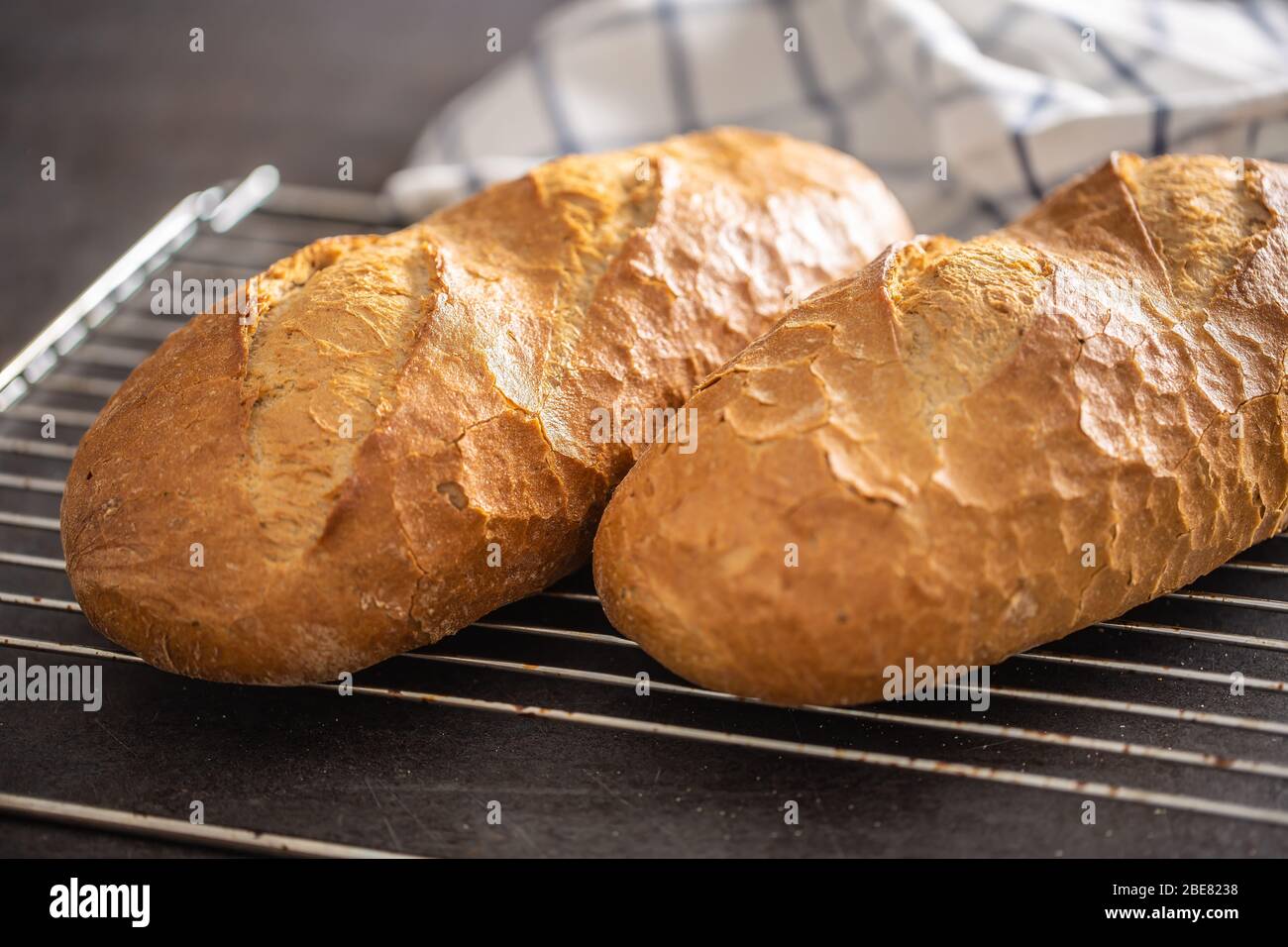 Due loafs di pane caldo cotto su una griglia del forno con un asciugamano sullo sfondo. Foto Stock