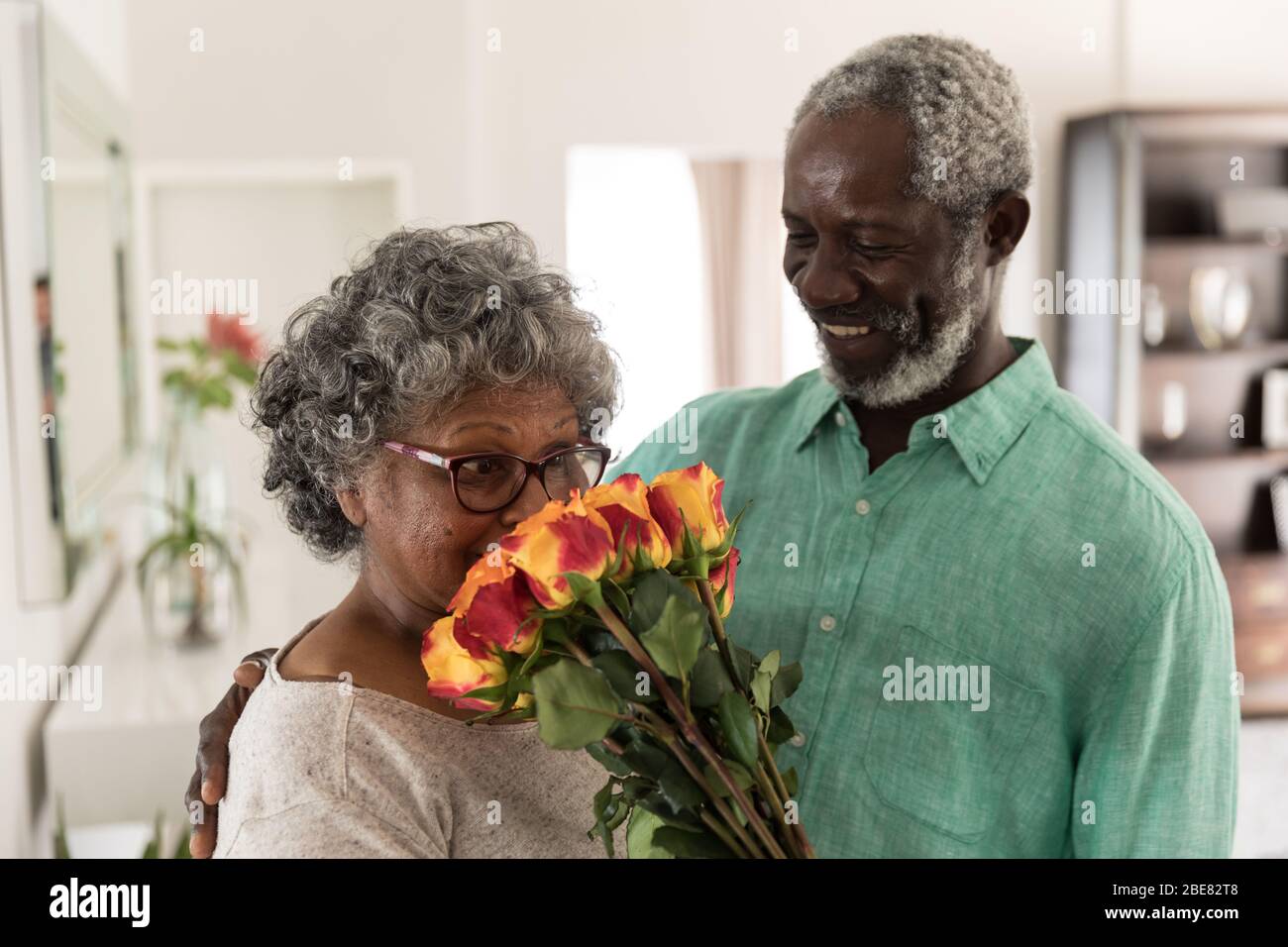 Un uomo africano americano anziano che offre i fiori a sua moglie Foto Stock