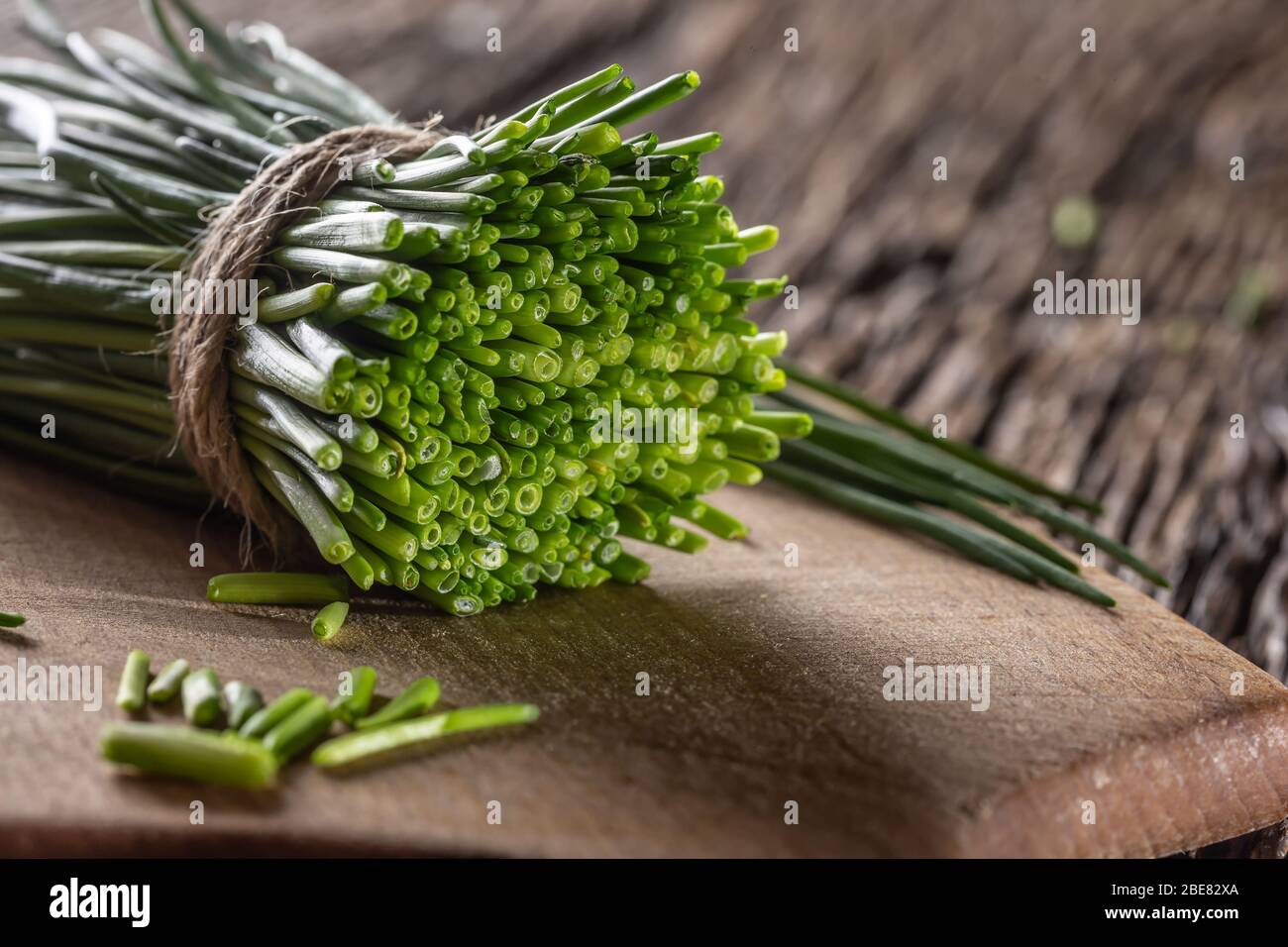 Mazzo di erba cipollina tagliata di fresco avvolta da uno spago di iuta su  un legno d'annata e tagliando il bordo Foto stock - Alamy