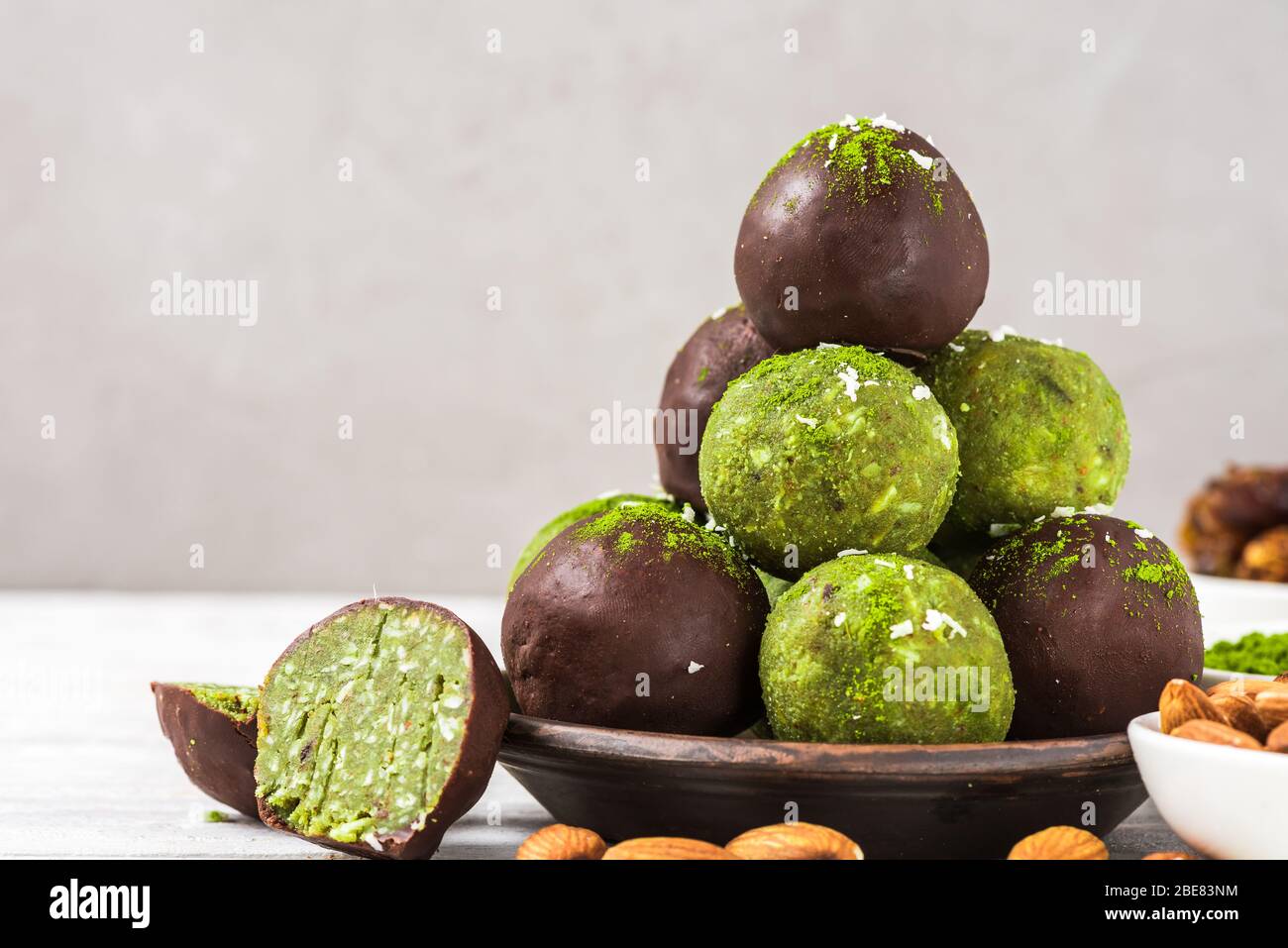 Palle di energia matcha verdi o morsi di energia con palle di energia in glassa di cioccolato. Spuntini salutari per la dieta vegana. Primo piano Foto Stock