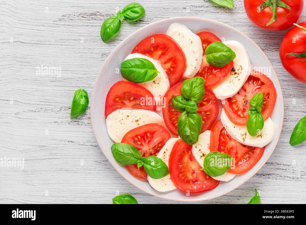Insalata caprese con pomodori maturi e mozzarella con foglie di basilico fresco in un piatto. Cucina italiana, vista dall'alto Foto Stock