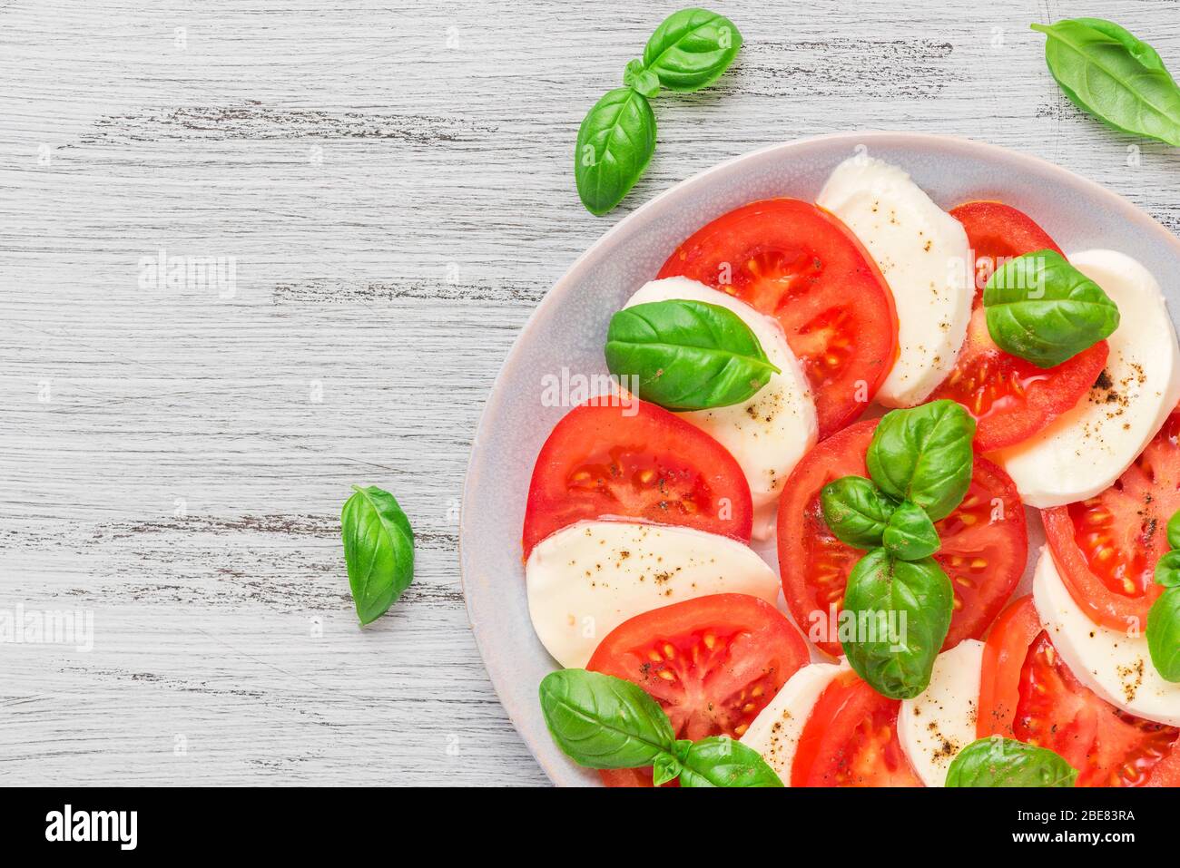 Insalata di caprese sana con pomodori maturi e mozzarella con foglie di basilico fresco. Cucina italiana, vista dall'alto con spazio per fotocopie Foto Stock