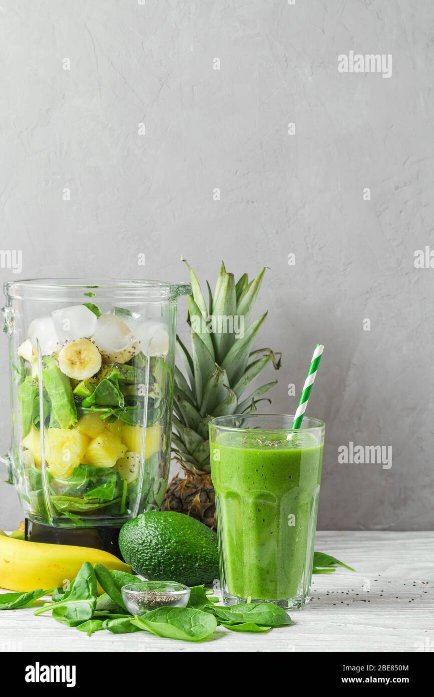 Bicchiere di disintossicazione verde con ingredienti freschi e succosi nel frullatore per preparare bevande salutari. Concetto di cottura vegano crudo. Orientamento verticale Foto Stock