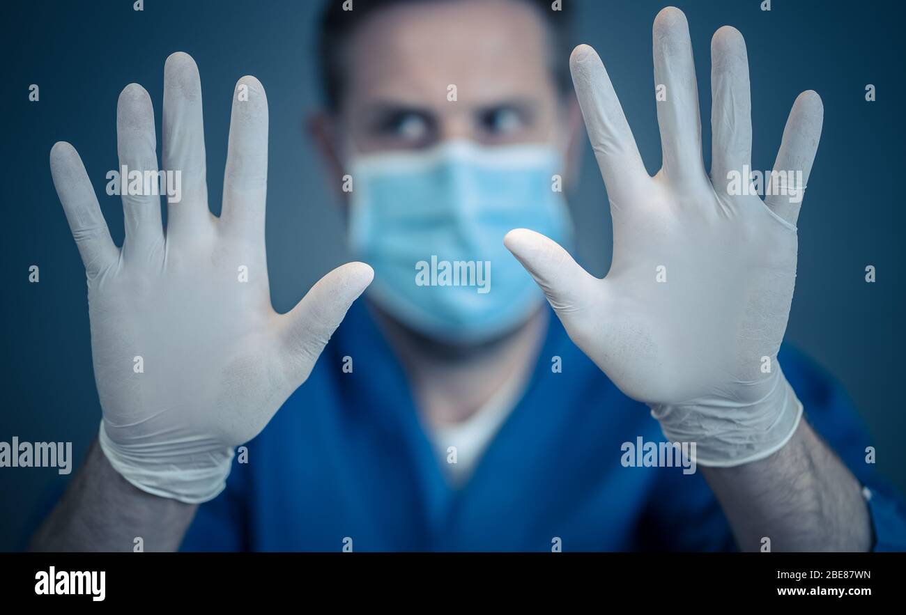 Focolaio COVID-19. Aiuto per fermare la diffusione del virus. Medico o infermiere che indossa maschera chirurgica facciale e guanti DPI che mostrano le mani in STOP gesture. Soggiorno s Foto Stock