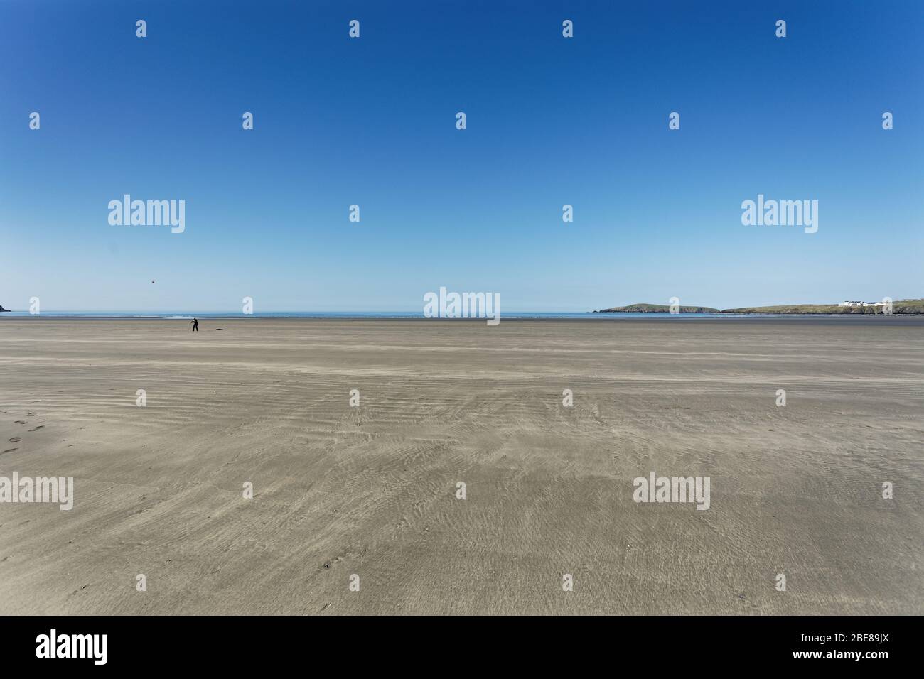 Nella foto: Un uomo solitario gioca con un frisbee a Poppit Sands, Galles, Regno Unito. Mercoledì 08 Aprile 2020 Foto Stock