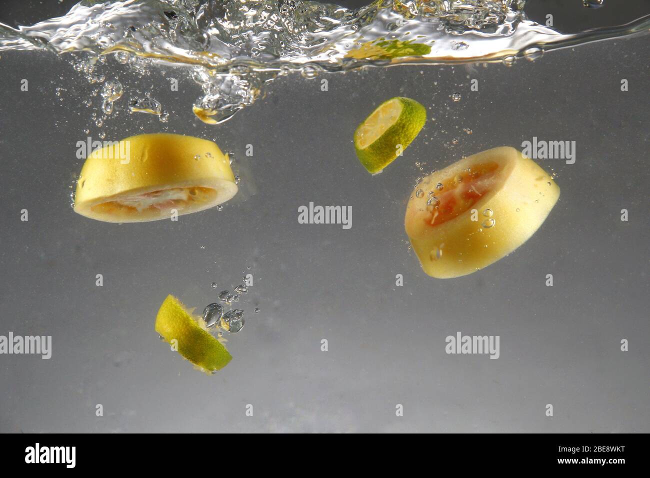 Foto di pomodoro fresco a fette e calamansi caduti in acqua Foto Stock