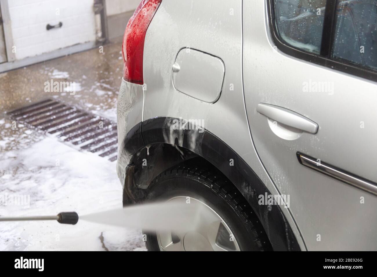 un processo di lavaggio interno di piccole auto argentate con flusso d'acqua da tubo a mano Foto Stock