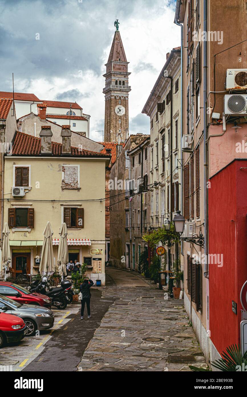 18 novembre 2019 - Pirano, Slovenia: Bella vista sugli orologi della vecchia torre e la vecchia strada stretta di Pirano - piccola città mediterranea in Slovenia Foto Stock