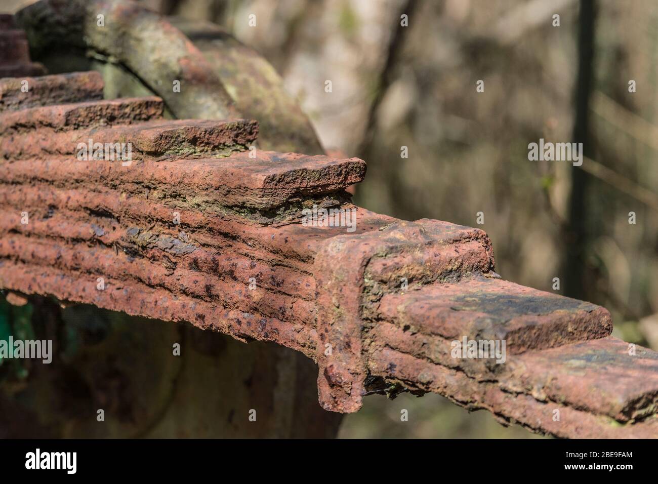 Colpo stretto di ruggine incrostato / arrugginito molla a balestra longitudinale in acciaio al sole. Per il metallo astratto, ossidazione del metallo, ruggine, nessuna molla rimasta al passo. Foto Stock
