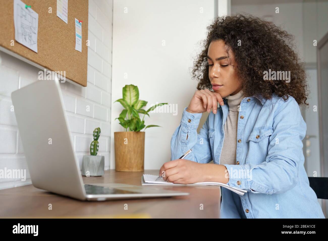 Serio studente universitario africano ragazza teen elearning a casa facendo appunti. Foto Stock