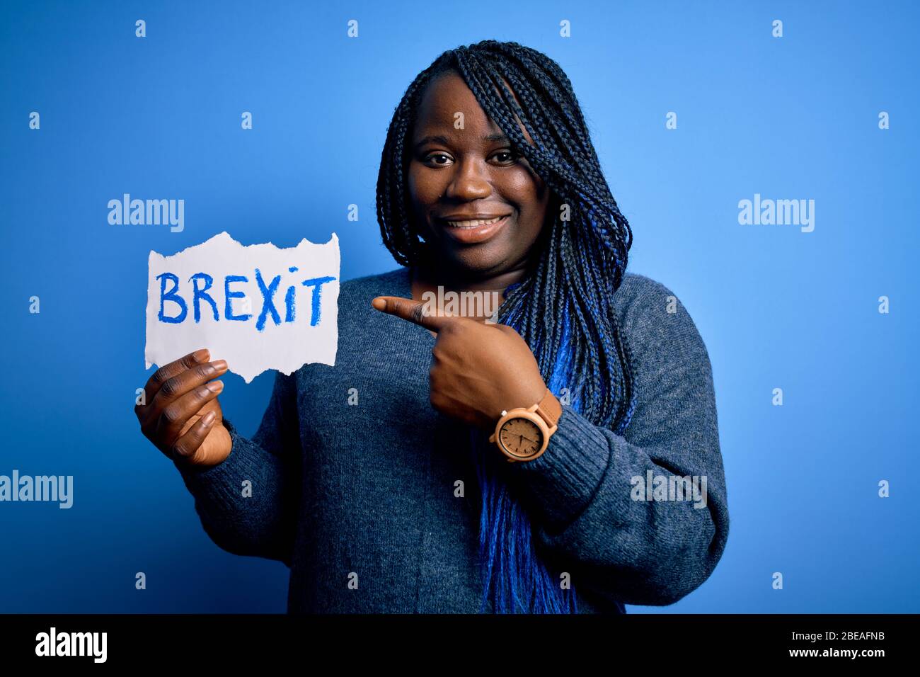 Giovane african american più donna con trecce tenere carta con messaggio brexit molto felice indicando con mano e dito Foto Stock