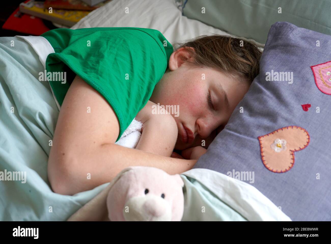 Ragazza che dorme nel letto con orsacchiotti Foto Stock