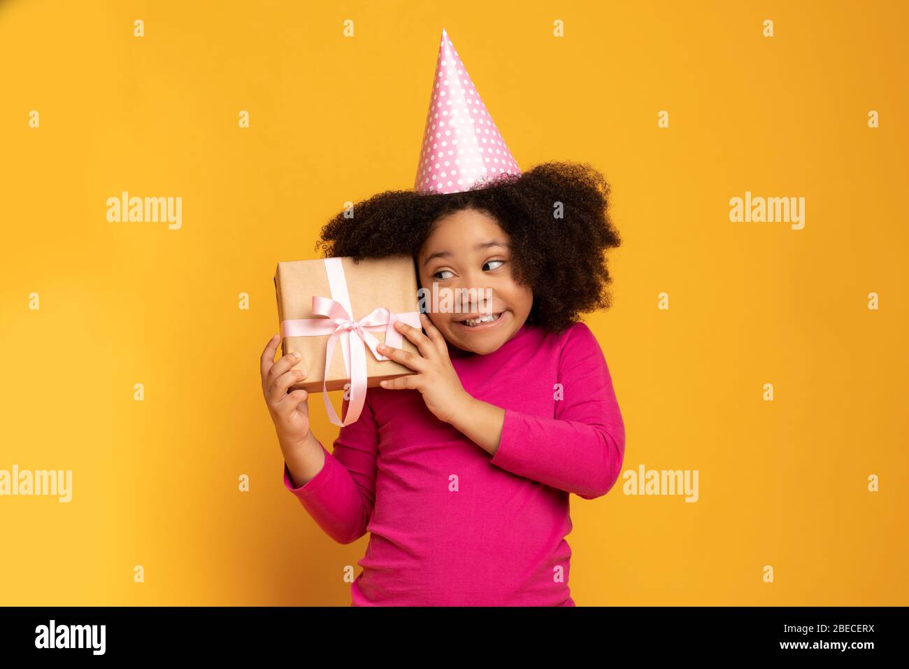 Regalo a sorpresa. Carino Little African American Birthday Girl Shaking Present Box Foto Stock