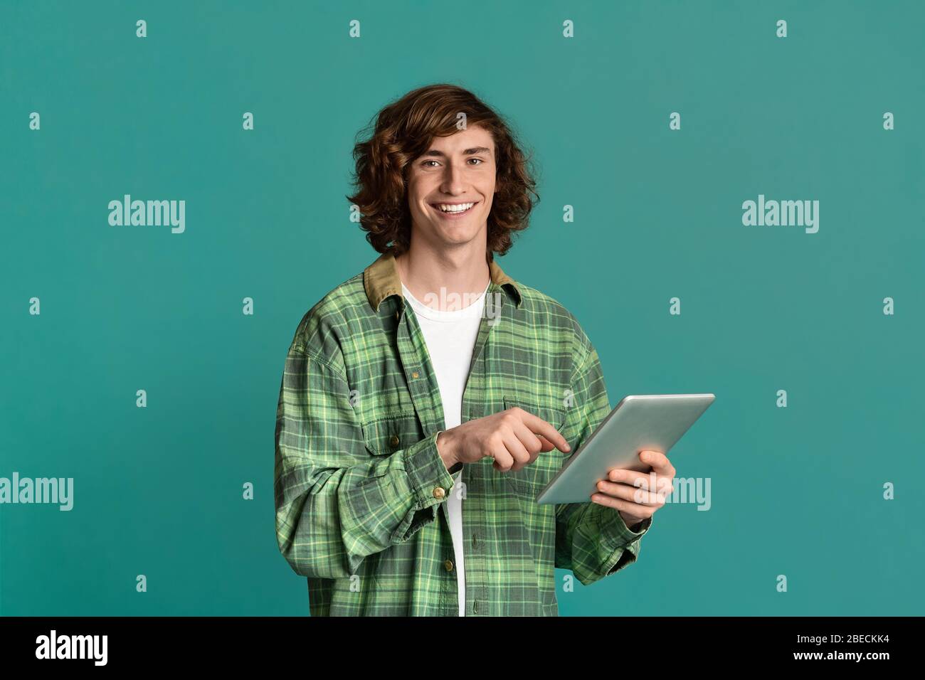 Comunicazione online. Ritratto di hipster millenario utilizzando un computer tablet su sfondo a colori Foto Stock