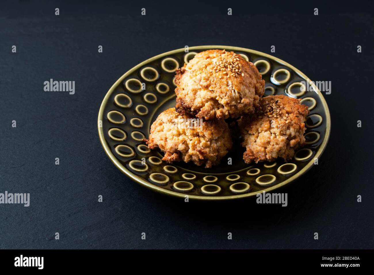 Cucina orientale concetto casalinga cinese Sesame cookie in piastra di ceramica verde su bordo di pietra ardesia nera con spazio copia Foto Stock