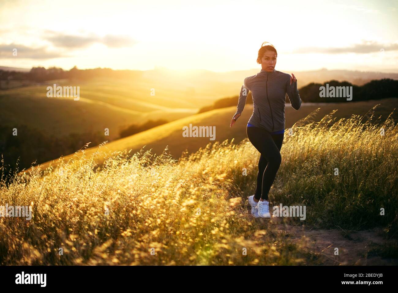 Giovane donna jogging in un paesaggio rurale al tramonto. Foto Stock
