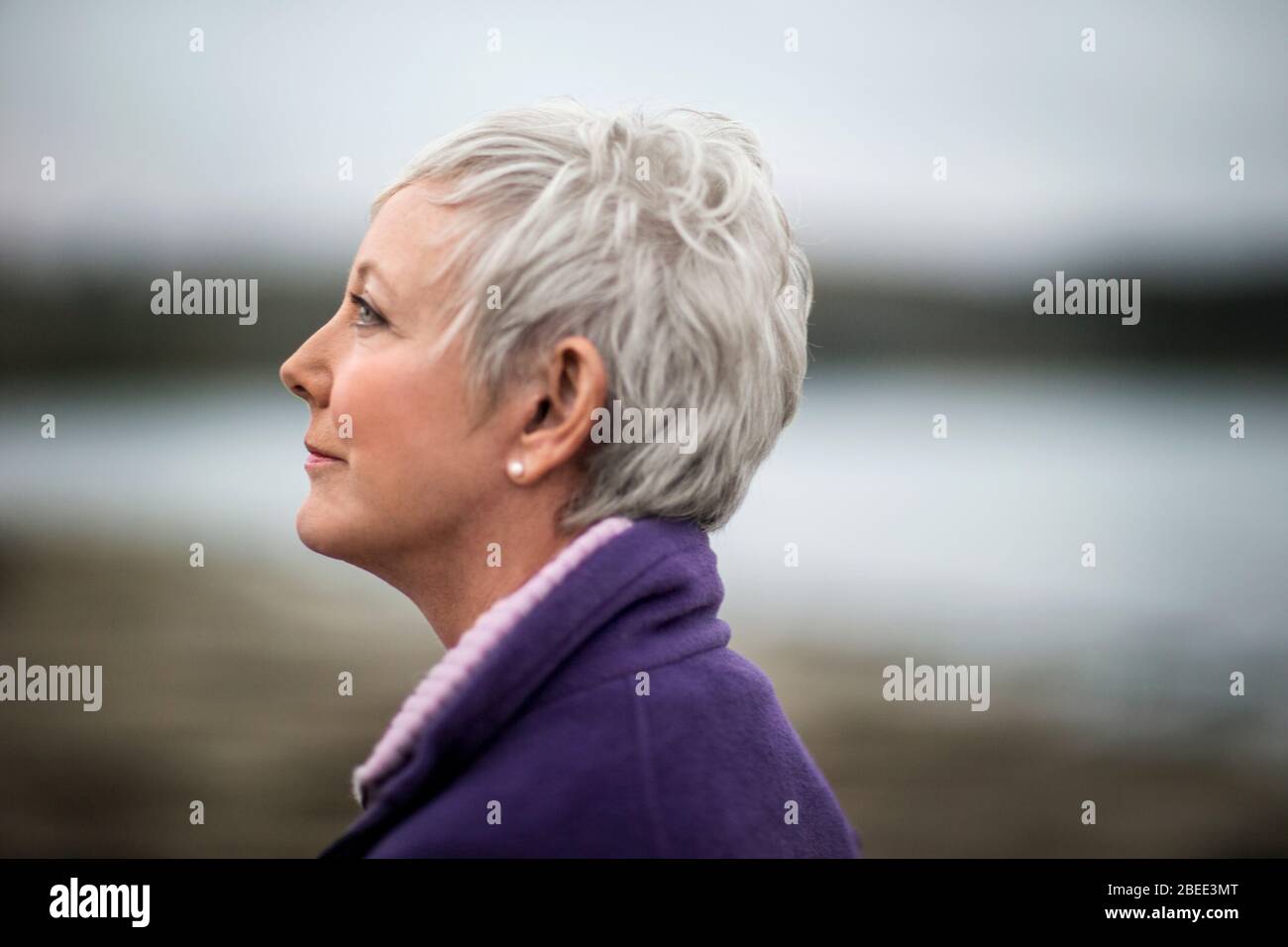 Ritratto di una donna matura godendo la vista sulla spiaggia in inverno. Foto Stock