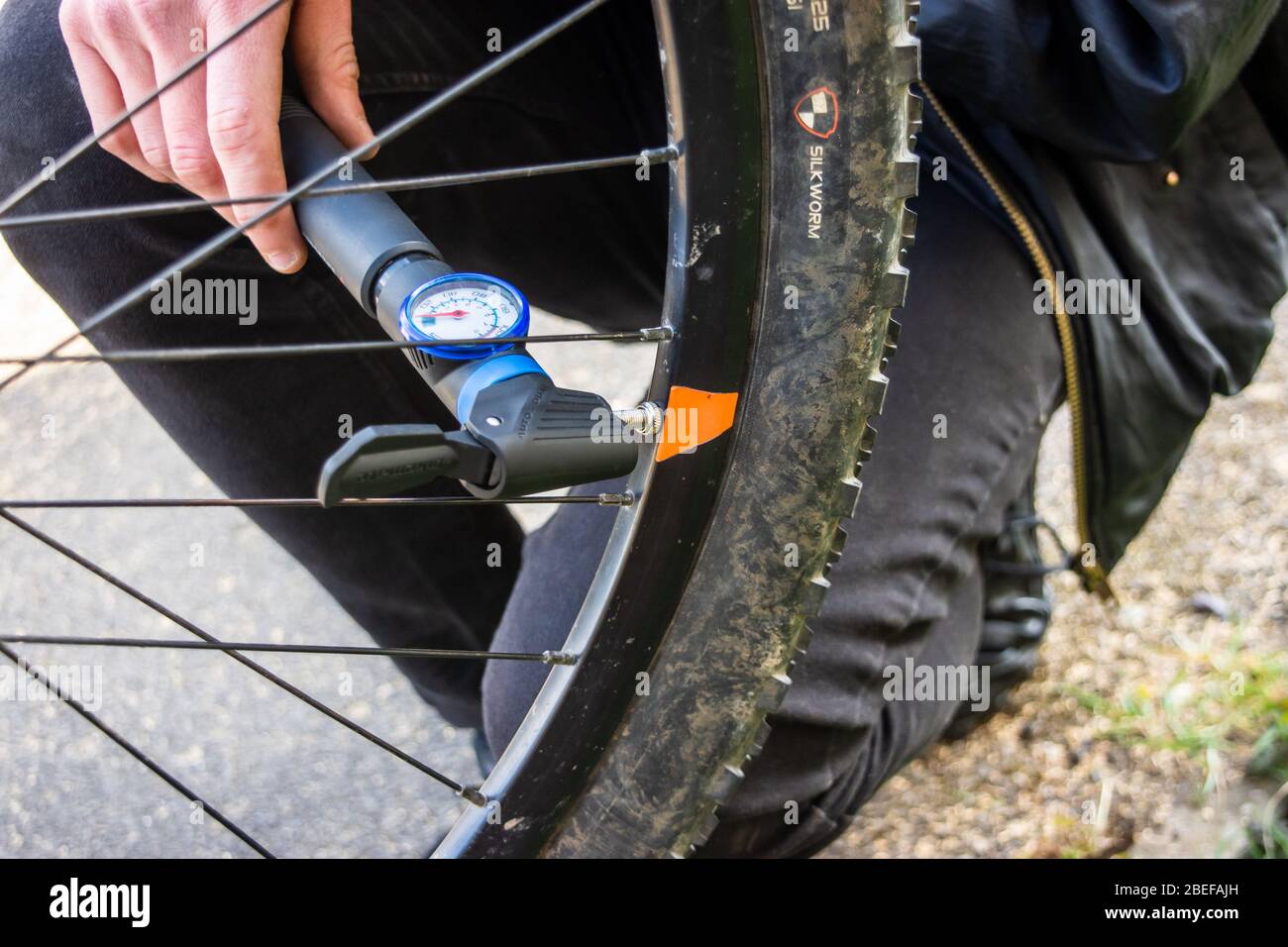 Una pompa manuale con un'unghetta di pressione fissata alla valvola di tipo a bicicletta per gonfiare lo pneumatico dopo una riparazione di foratura Foto Stock