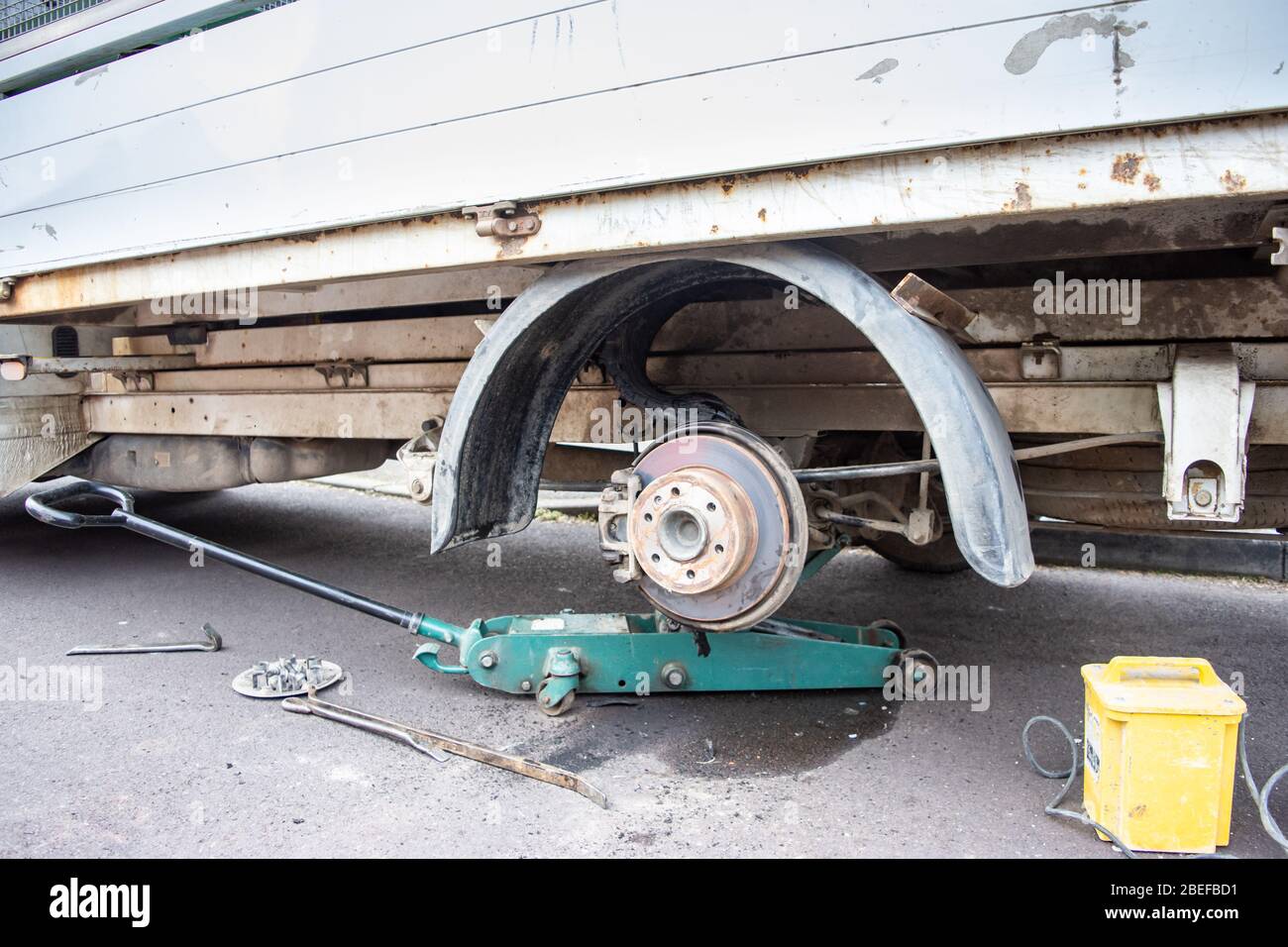 Il mozzo ruota e il parafango di un furgone che ha avuto uno scoppio pneumatico con i resti dello pneumatico aggrovigliati intorno all'assale Foto Stock