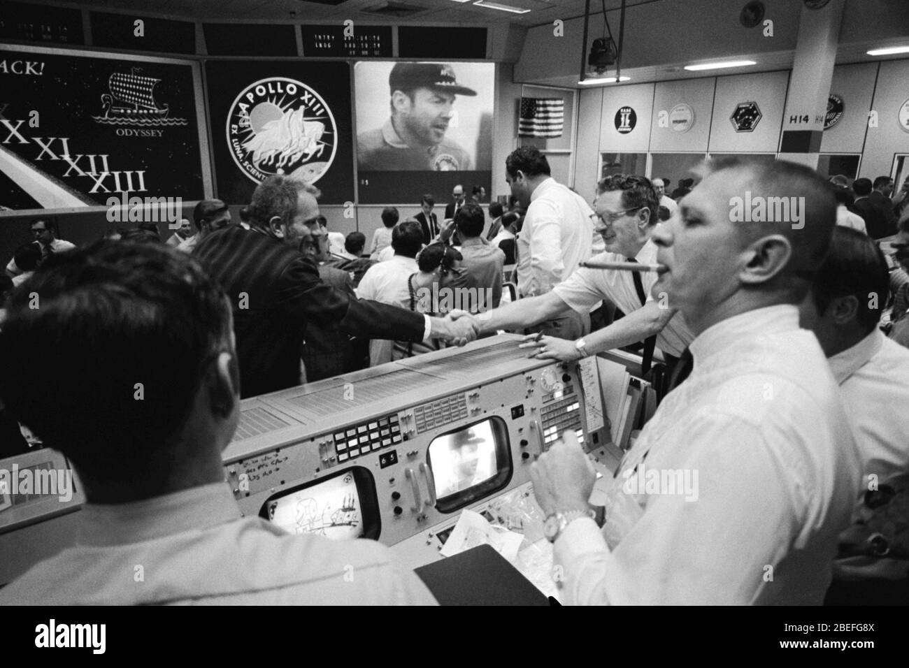Deke Slayton (nella camicia nera, a sinistra del centro), direttore delle operazioni di volo dell'equipaggio e Chester M. Lee si scuotono le mani in Mission Control, mentre Rocco Petrone guarda il comandante dell'Apollo 13 Jim Lovell sullo schermo. Apollo 13, lanciato il 11 aprile 1970, è stata la terza missione della NASA sulla luna. Due giorni dopo, il 13 aprile, mentre si dirigeva verso la superficie lunare, un guasto nell'impianto elettrico di uno dei serbatoi di ossigeno del modulo di servizio ha prodotto un'esplosione che ha causato il guasto di entrambi i serbatoi di ossigeno e ha anche causato una perdita di energia elettrica. Con la missione interrotta, una squadra dedicata nell'Apollo mi Foto Stock