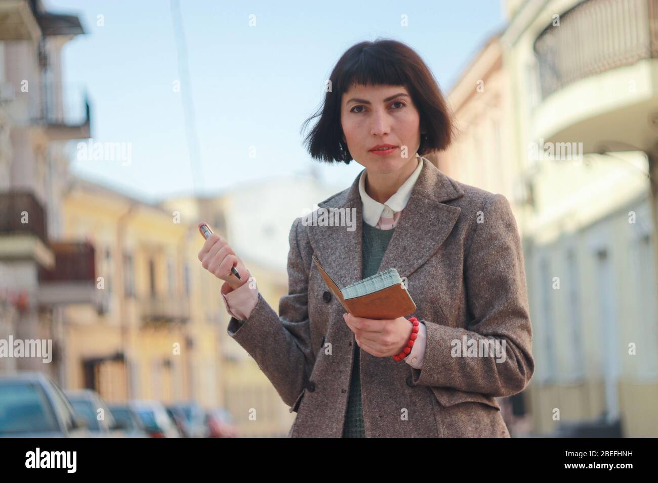 Giovane donna prende appunti sulla strada. Scambio studente alla ricerca di alloggio in affitto. Ricerca di alloggi e appartamenti. Foto Stock